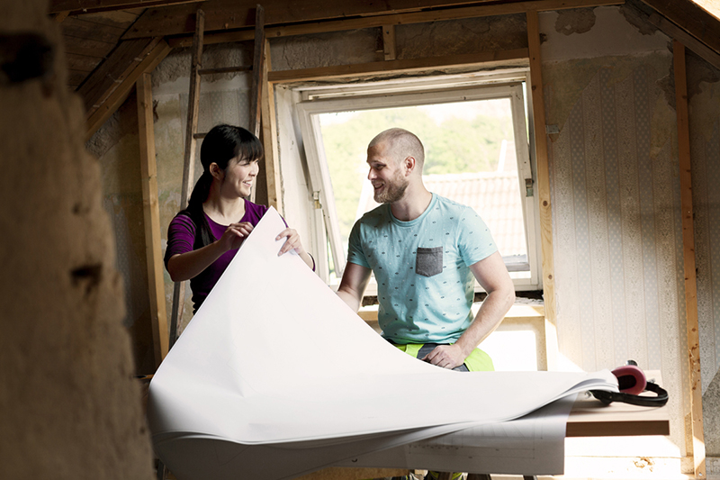Couple looking at renovation plans while remodeling a home. 